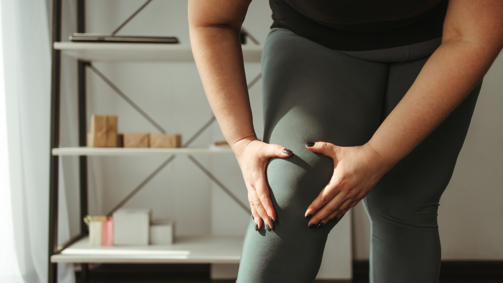 Woman wearing leggings holds her knee in pain. (Photo: Getty Images)